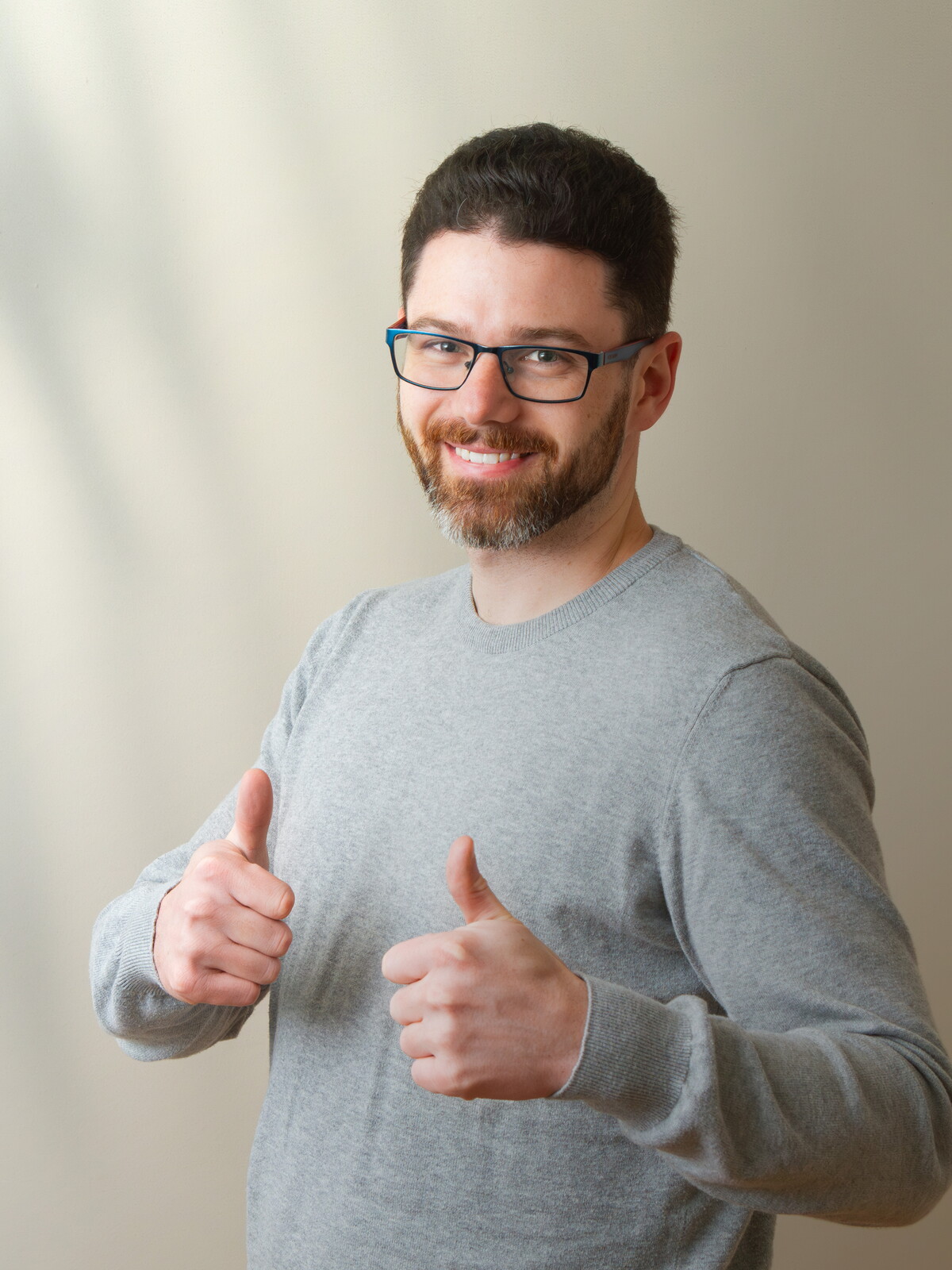 Markus im grauen Pullover hält grinsend beide Daumen nach oben.