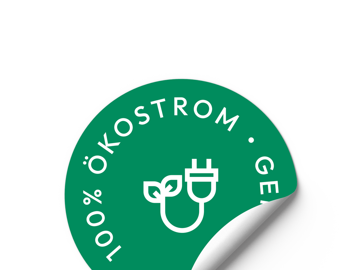 Ein runder grüner Aufkleber mit weißer Schrift „100 % Ökostrom“ und einem Stecker-Symbol mit Blättern. Eine Ecke des Aufklebers löst sich und rollt sich nach oben.